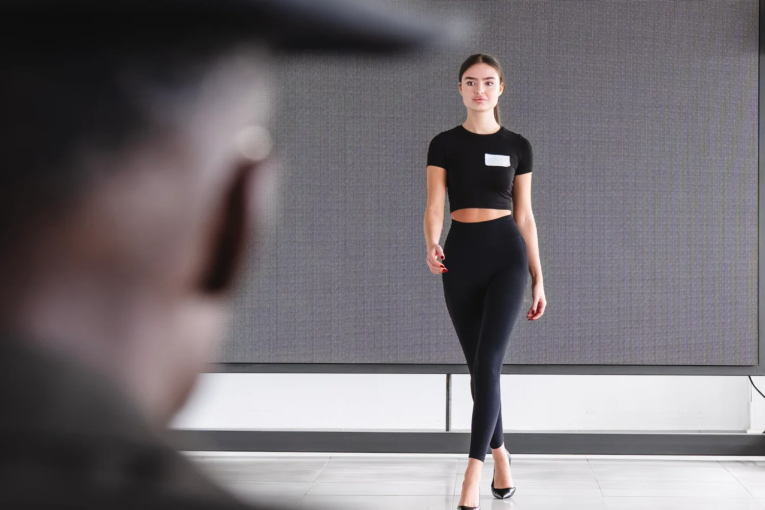 Una candidata camina hacia el jurado en el casting de Mallorca Fashion Days 2026, vista por detrás de Sadio Konte, con sombrero