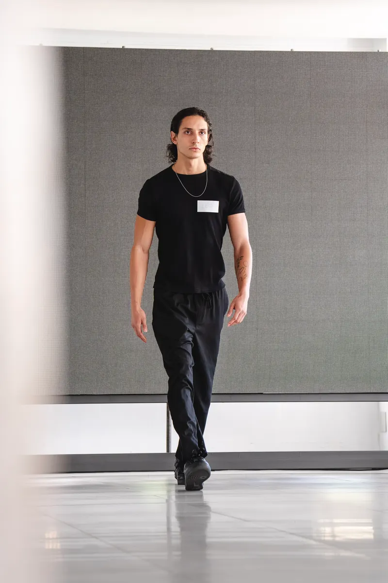 Un candidato de pelo largo, con camiseta y pantalón negros, hace la prueba de pasarela