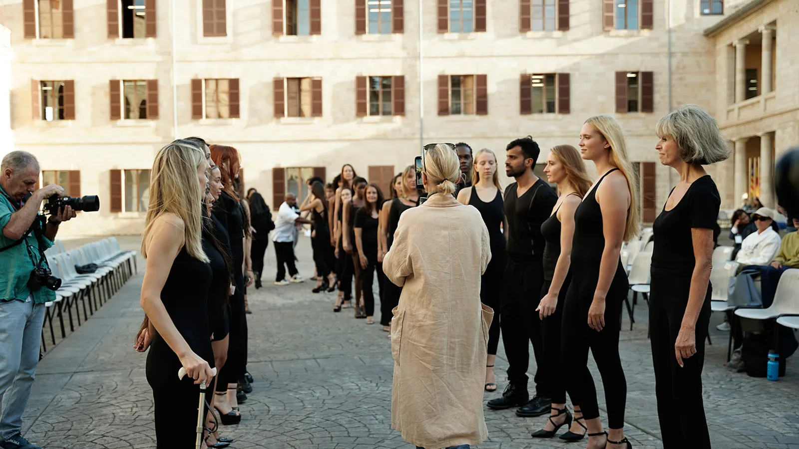 Un fotógrafo trabaja durante el casting de 2025 en el patio de La Misericòrdia, con los modelos en fila