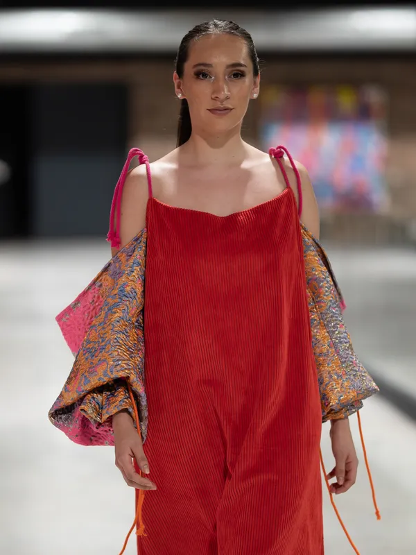 Ein Model auf dem Laufsteg 2025 in einem roten Cordkleid mit Ärmeln im Paisleymuster